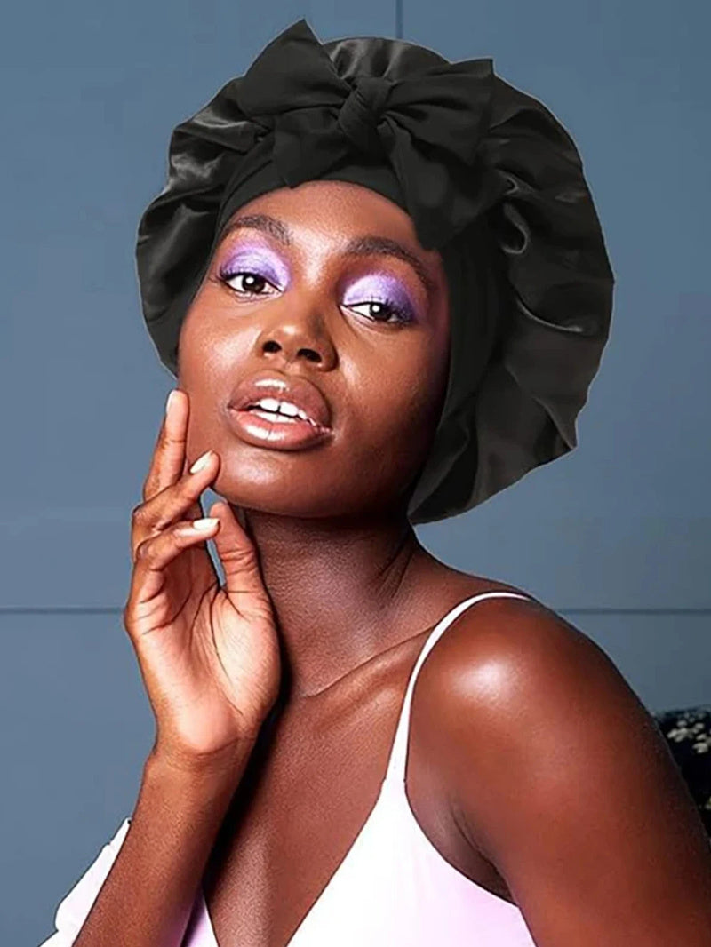 Woman wearing a black satin head wrap against a gray background
